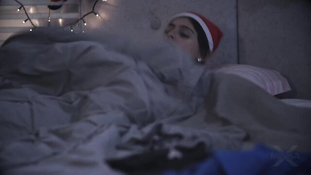 Angel Windell smoking in bed wearing Santa hat, cozy Christmas tease