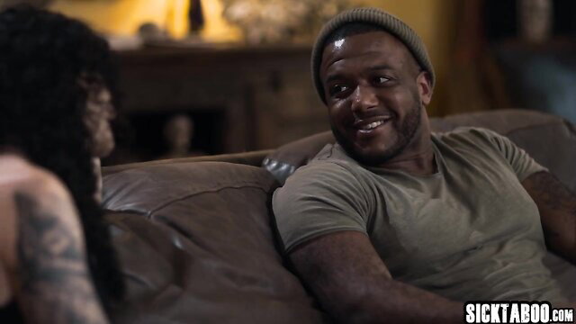 Exciting cougar with black hair tattoos chats with muscular black guy in beanie