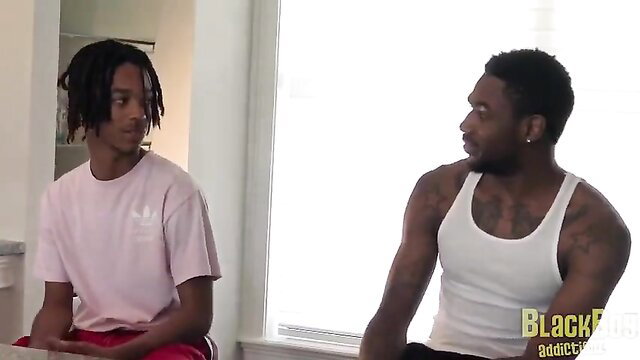 Two young black guys in tank tops and shorts, close-up intimate moment