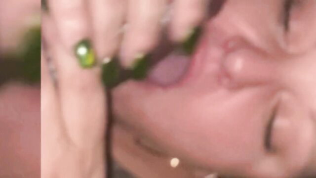 Closeup of woman's open mouth and tongue with hand and green ring