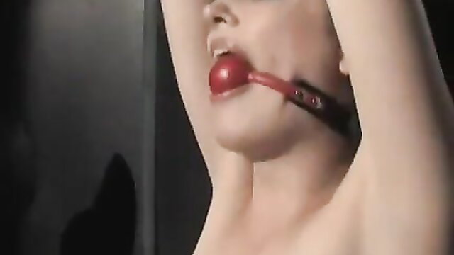 Hot blonde gagged with red ball gag, arms up in BDSM cell tease