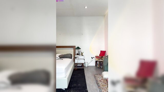 Mia Khalifa in modern bedroom with bed and red chair