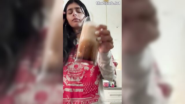Mia Khalifa sipping drink in tight red top, teasing cleavage closeup