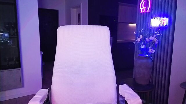 Janemiss blonde camgirl in white chair, neon ass sign glows