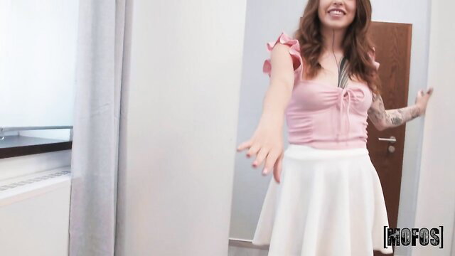 Johnny Love in pink top and white skirt poses seductively