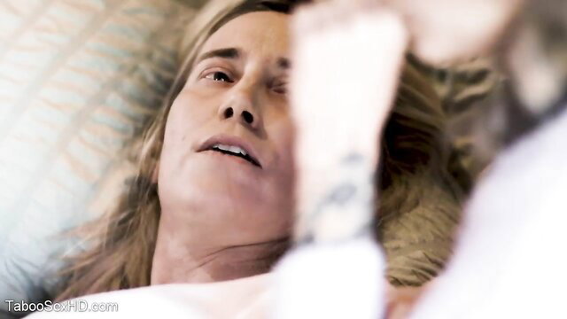 Blonde woman with long hair lying in bed, close-up face during blowjob tease