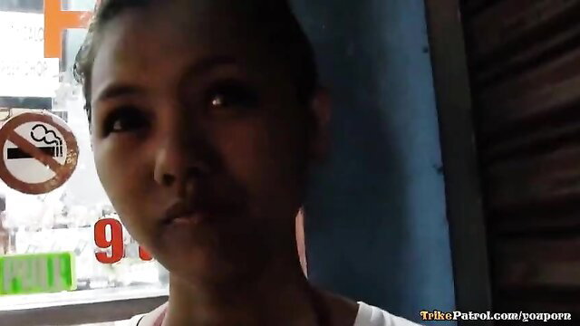 Cute Filipina teen with braces in tight white tank top, no-smoking sign background