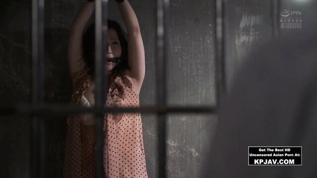 Japanese MILF bound arms up in polka dot dress jail cell bondage