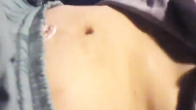 Closeup of woman's pale belly with navel piercing in open green top