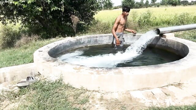 Shirtless young Pakistani twink bare-chested at rural tubewell, water splashing