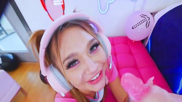 Pretty Asian gamer girl in pink headset sucks pink dildo closeup