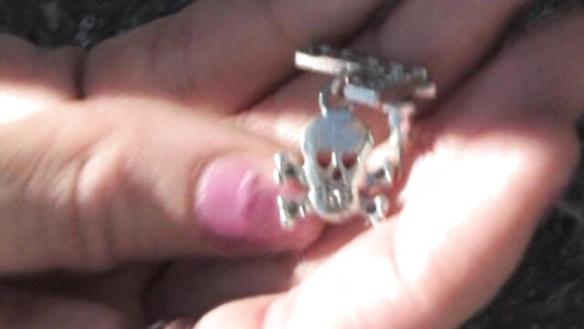 Sophie Dee silver skull pendant closeup hand tease