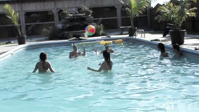Nude lesbians playing with beach ball in outdoor pool