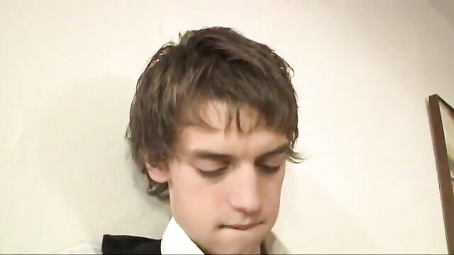 Handsome young man with tousled brown hair looking down in low-light closeup