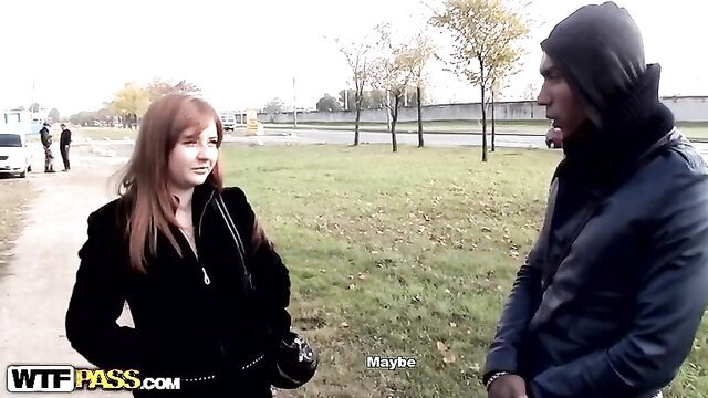 Busty redhead in black coat talking to hooded guy in park pickup