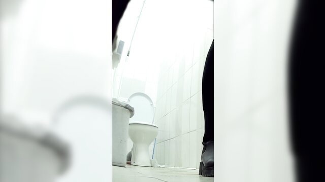 Spy cam of woman's legs and black boots by toilet in shopping center bathroom