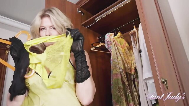 Blonde mature Diana in yellow lingerie holds torn panties in closet