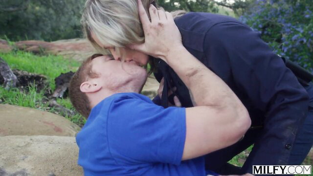 Blonde nurse kissing redhead guy passionately outdoors in forest