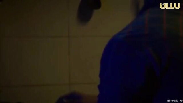 Blurred man in plaid shirt from behind in dim room, Ullu adult video thumbnail