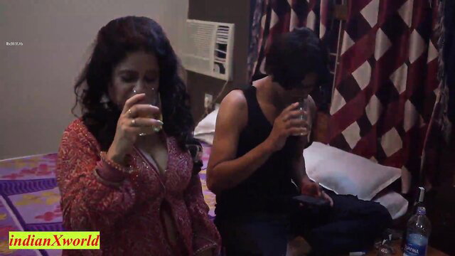 Indian aunty in deep cleavage top drinks with man on bed in steamy scene