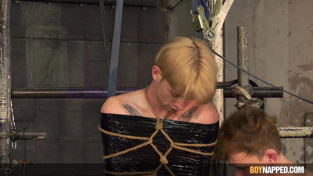 Blond twink bound tightly in black duct tape bondage