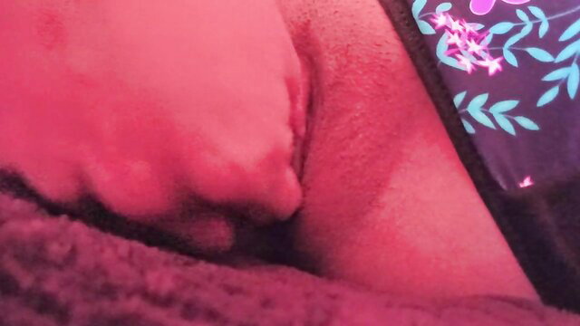 Close-up view of woman's wet pink pussy lips spread on bed