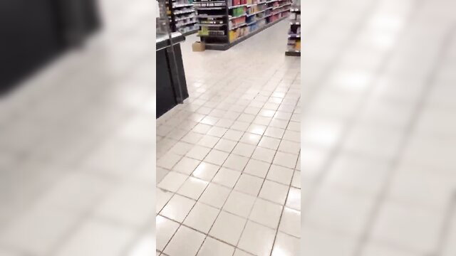 Blurry public supermarket aisle with shelves and checkout, no visible nudity