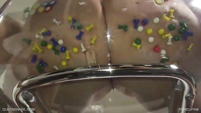 Nude woman buttocks covered in colorful thumbtacks, wet skin shining