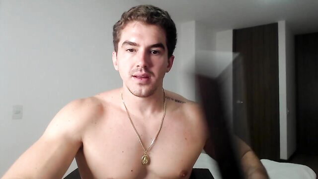 Muscular Latino guy shirtless, gold chain necklace, intense gaze