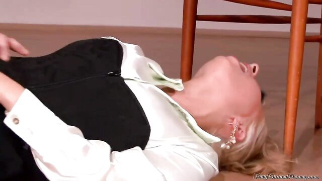 Blonde MILF in corset top lies arched on floor, teasing golden shower threesome session