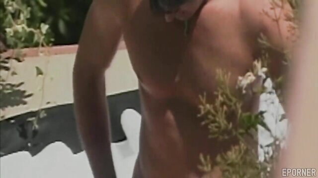 Muscular Latino man nude in outdoor hot tub with plants