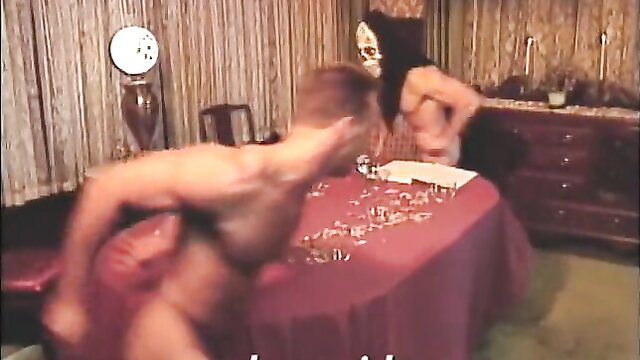 Nude couple in intense threesome with masked woman on red table