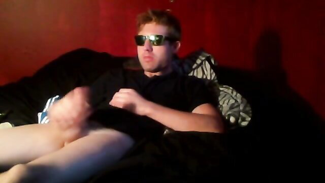 Redhead guy in shades jerks off in bed, big dick exposed