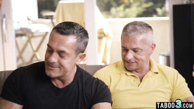 Two handsome mature Latino daddies smiling close on balcony