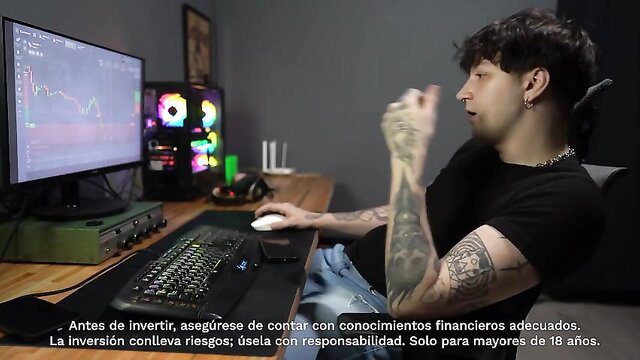 Tattooed Latino gamer guy at desk with RGB PC setup, trading screens