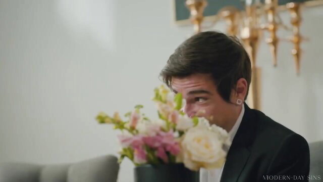 Handsome man hiding behind flowers smirking, tuxedo formal