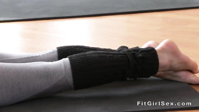 Fit girl in yoga pants and leg warmers lying on mat, sexy pose