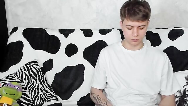 Young white guy with tattoos sits casually on couch in amateur cam sex thumbnail