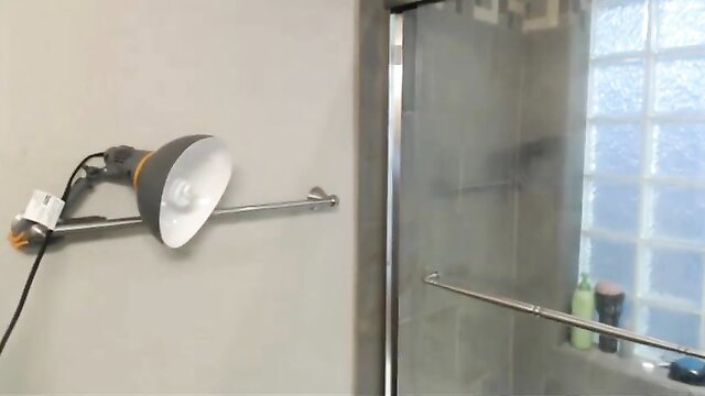 Shower door with mounted hairdryer lamp in steamy bathroom