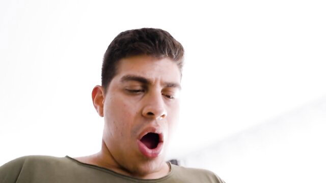 Handsome Latino man yawning wide in tight green shirt closeup