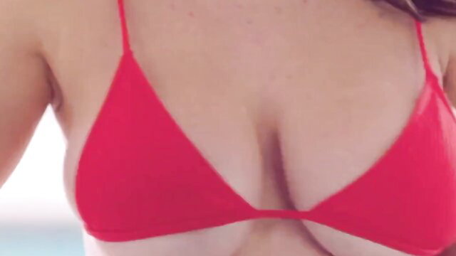 Mature brunette in skimpy red triangle bikini top, deep cleavage tease