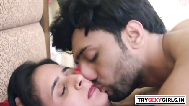Indian couple in bed, man kissing busty woman's face passionately