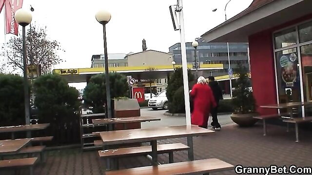 Hungry blonde grandma in red coat at McDonald's Agip gas station