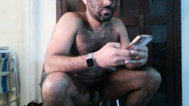 Hairy bearded Arab man squatting nude holding phone in gay thumbnail