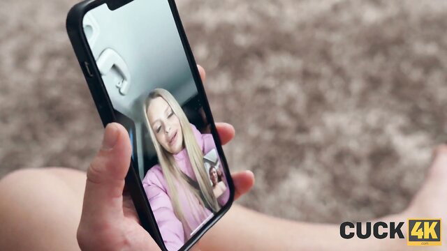 Blonde babe in pink top on video call to man holding phone, cuckold tease