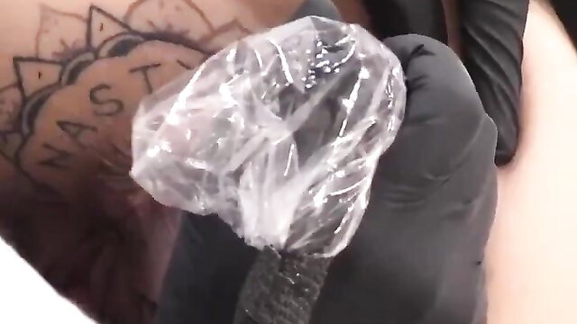 Tattoo artist inks whore's asshole closeup with gloved hand
