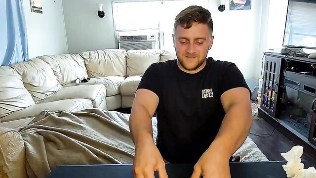 Muscular white guy with buzzed hair flexing arms in tight black tee