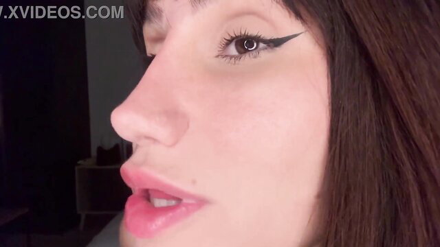Closeup of sexy brunette's glossy lips and sharp eyeliner in teasing profile view