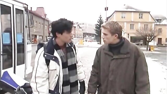 Two handsome young men in winter coats talking intimately on snowy street