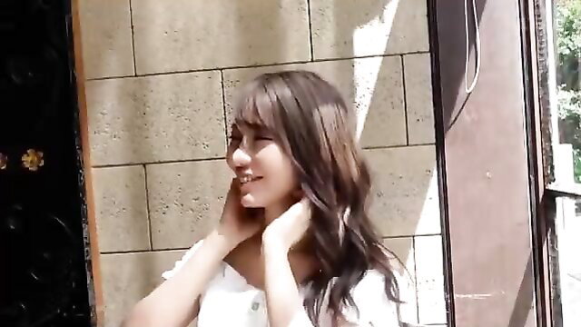 Asian beauty with long wavy brown hair smiling, hands on neck in white off-shoulder top